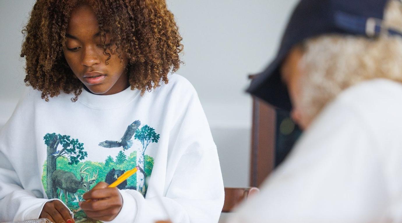 a student sits at a table and writes